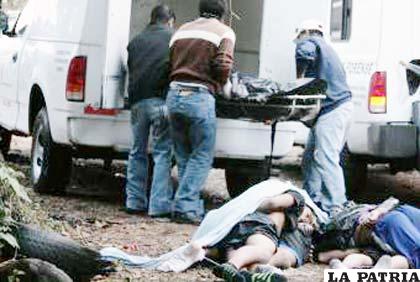 Efectivos policiales levantando los cuerpos sin vida de las personas asesinadas por “narcos”