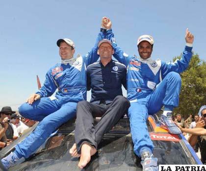 Carlos Sainz ubicado en tercer lugar, y Nasser Al Attiyah, ganador del Dakar en autos. Al centro aparece el director de la escudcería Wolkswagen.