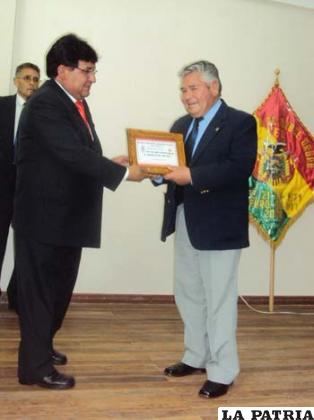 Lizandro García entrega una plaqueta a Juan Medina, titular de la AFO