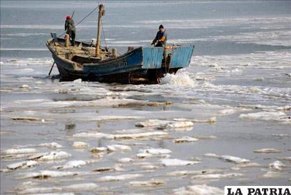 Un par de pescadores intentan maniobrar con su barco por las aguas heladas en la bahía Jiaozhou, Qingdao, provincia oriental china de Shandong