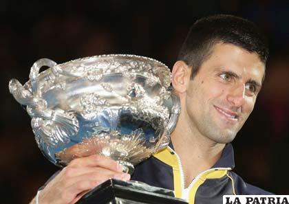 Novak Djokovic con el trofeo en alto, luego de ganar el Abierto de Australia