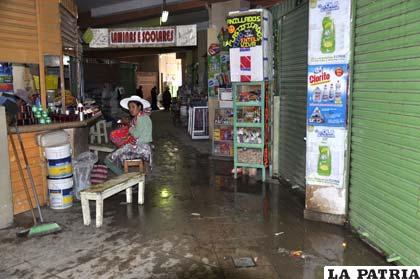 Comerciantes venden en medio del agua que cae de las goteras