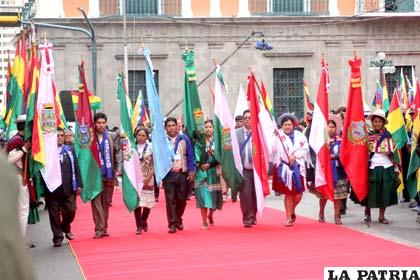 Desfile de representantes de los nueve departamentos llevando la bandera de su región
