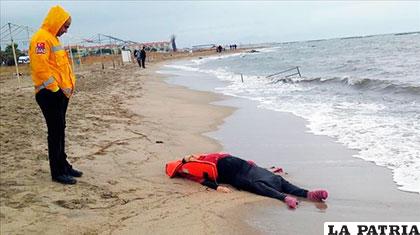 Miembro de los equipos de rescate, contempla el cuerpo de un inmigrante en la playa /zetaestaticos.com