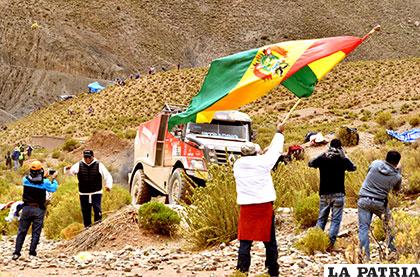 El espectador haciendo flamear la bandera boliviana tras el paso de un camión
