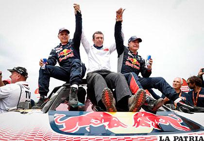Carlos Sainz (derecha) celebra con su copiloto Lucas Cruz (izquierda) y el manager del equipo Bruno Famine (centro) luego de ganar el Dakar 2018 /DAKAR .COM
