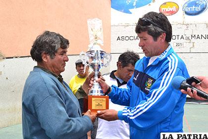 Entrega del trofeo de campeón al representante del equipo de Río Ingenio 