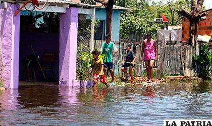 Un grupo de niños caminan frente a una casa inundada en un barrio de Asunción, Paraguay