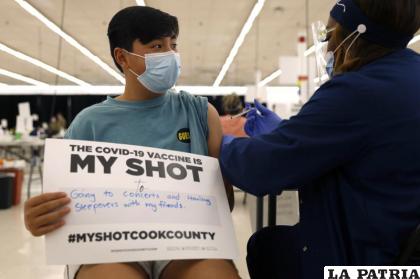 Lucas Kittikamron-Mora, de 13 años, muestra un cartel en apoyo a la vacuna contra el Covid-19 mientras recibe su primera dosis de Pfizer 
/AP Foto/Shafkat Anowar, archivo
