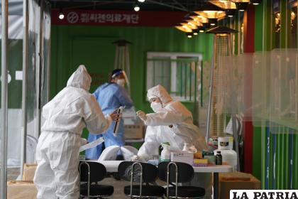 Trabajadores de salud con equipo de protección se preparan para tomar muestras en una clínica temporal de detección del coronavirus 
/AP Foto/Lee Jin-man
