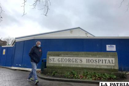 Un transeúnte camina frente a un centro de pruebas de COVID-19 que fue montado en el Hospital St. George’s en Londres / Foto AP / Kirsty Wigglesworth