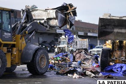 Palas mecánicas levantan tiendas de campaña, muebles y otros objetos al desalojar un campamento de indigentes /AP Foto /Charles Krupa