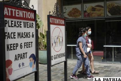 Personas con mascarillas caminan en el exterior de un centro comercial /AP Foto/Damian Dovarganes, archivo