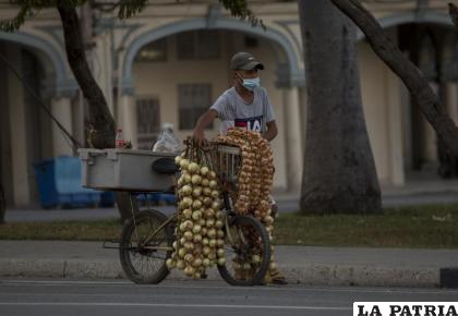 Un hombre con una mascarilla protectora vende ajos y cebollas en La Habana / AP Foto/Ismael Francisco