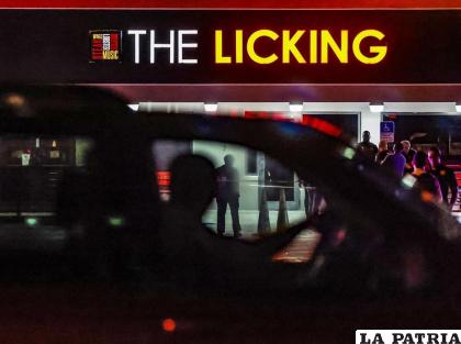 Transeúntes observan cómo los policías de Miami Gardens trabajan en los alrededores del restaurante The Licking /AP