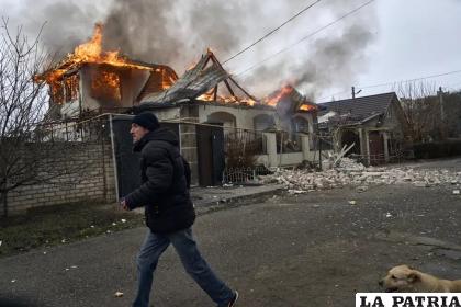 Un residente pasa junto a una casa en llamas tras un bombardeo ruso en Jersón /AP Foto/LIBKOS