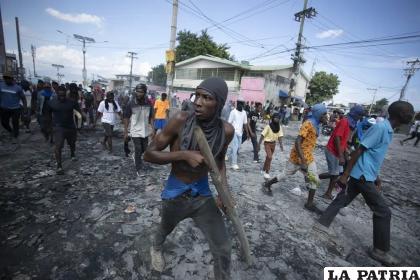 Un manifestante lleva un trozo de madera que simula un arma durante una protesta en la que se exigió la renuncia del primer ministro Ariel Henry /AP Foto/Odelyn Joseph
