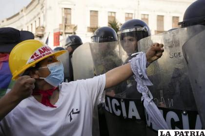 Un manifestante de oposición al gobierno encara a una línea de policías antimotines en Lima /AP Foto/Guadalupe Pardo