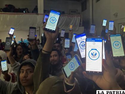 Decenas de migrantes muestran sus teléfonos con la app CBPOne, en un albergue en Tijuana, México / AP Foto/Elliot Spagat