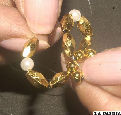 PASO 3
Pasar a la siguiente perla, poner dos perlas doradas una blanca y otra dorada enlazando al pétalo de lado.
