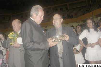 El dirigente del Comité Técnico de la Conmebol, Paraguazú Ficher Figueredo, recibe una plaqueta recordatoria de manos de Donald García, dirigente de la FBF