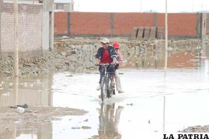 Los vecinos se dan modos para circular en medio del agua acumulada que además remoja los cimientos de las viviendas