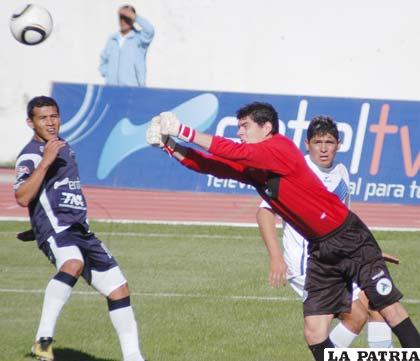 Carlos Lampe, despeja el balón ante la mirada de Alan Loras y Luis Palacios