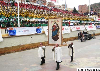 Feligreses llevan la imagen de la Virgen en andas, mientras las bandas interpretan la plegaria A vuestros pies Madre