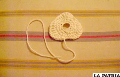 PASO 3
Puedes optar por dejarlo así, pero queda mucho más bonito con la cobertura.
Para hacer la cobertura usamos lana blanca, como si fuera una rosquilla con nata.
Comenzamos como con la rosquilla, tejiendo una cadeneta de 12 puntos cuyo último punto uniremos al primero formando un círculo.
Vuelta 1, aumentar en todos los puntos hasta tener 24.
En la vuelta 2 puedes mezclar puntos bajos, altos y rasos, siempre y cuando aumentes en uno y tejas un punto en el siguiente y obtengas 36 puntos en la vuelta. Hemos optado por repetir este patrón en la vuelta: un punto bajo, un punto medio alto, dos puntos altos, un punto medio alto y un punto bajo. Así se consigue un efecto ondulado pero no tiene por qué ser regular, ya que estamos tejiendo una cobertura de nata que, en la vida real, no sería regular