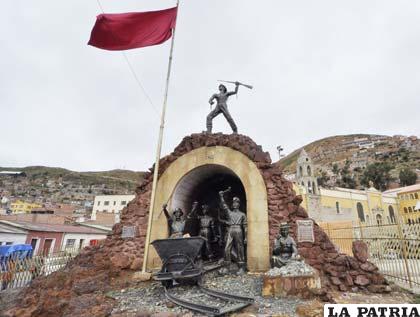 Bandera rojo carmesí flameando junto al monumento al minero