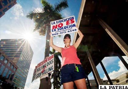 Dos manifestantes sostienen pancartas en contra de la pena de muerte, en las afueras de la prisión federal de Borward County en Florida