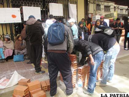 Un grupo de postulantes protestan en la puerta de la UTO armando un tapiado