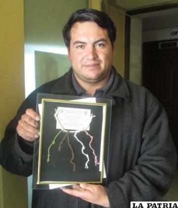 El presidente de la Asociación de Notarios de Oruro, Jhonny Castro, muestra el galardón recibido