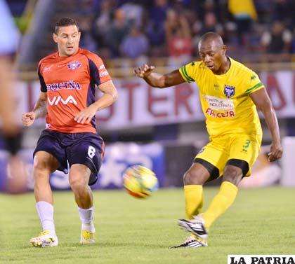 Rolando Barra rechaza la pelota ante la mirada de Carlos Neumann