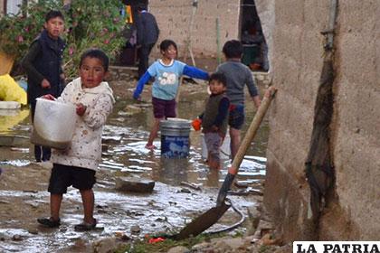 Niños sacando el agua de su casa, también fueron afectados