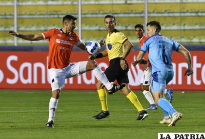 Alex Granell jugador de Bolívar intenta evitar que su rival domine el balón /APG