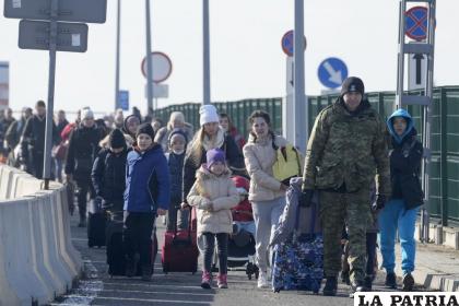 Un guardia fronterizo polaco (derecha) ayuda a los refugiados ucranianos a llegar a Polonia en el cruce fronterizo /AP Foto/Czarek Sokolowski
