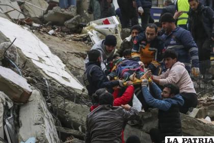 Gente y equipos de rescatistas trasladan a una persona en camilla desde un edificio derruido en Adana, Turquía /IHA agency via AP