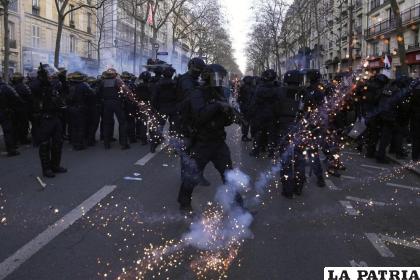 Policías antimotines en sus puestos mientras les lanzan proyectiles en una manifestación /AP Foto/Michel Euler)