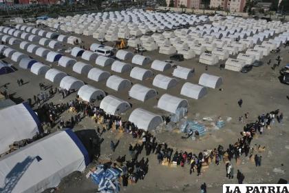 Personas que perdieron sus hogares en el terremoto que sacudió Turquía y Siria se forman para recibir ayuda en un campamento improvisado /AP Foto/Hussein Malla