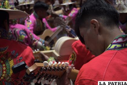 Músicos afinan su guitarrón para realizar una excelente presentación ante la comitiva de autoridades