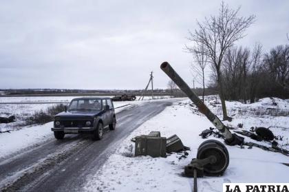 Un auto pasa junto a un tanque destruido en un antiguo puesto de las fuerzas rusas /AP Foto/Evgeniy Maloletka