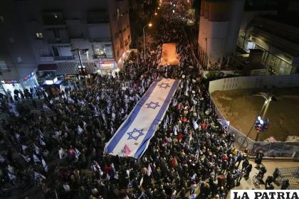 Israelíes marchan con una enorme bandera nacional durante una protesta contra los planes de reforma judicial /AP Foto/Tsafrir Abayov