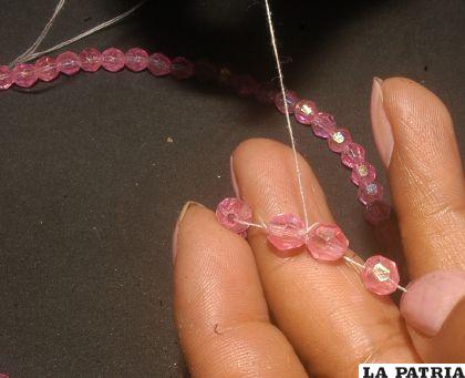 PASO 2
Contando desde el centro del collar, cinco perlas a un costado y cinco al otro, e insertar seis perlas e introducir en la cuarta perla.
