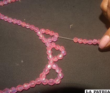 PASO 4
Introduciendo la aguja con el hilo por la perla del medio de la primera ondulación, insertar seis perlas y unir en la tercera perla de la ondulación de al lado. 
