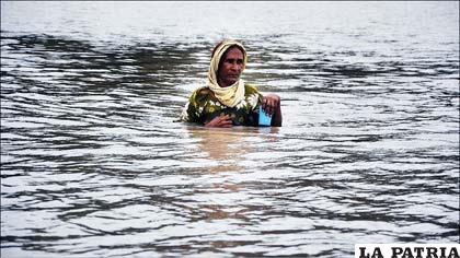 Una mujer en la aldea de Basera, Pakistán, trata de cruzar un campo inundado. Está sosteniendo un vaso de plástico con un poco de agua. La foto fue tomada el 21 de septiembre de 2010, ocho meses después de las inundaciones en ese país, que causaron más de 170.000 víctimas y casi 20 millones de damnificados.