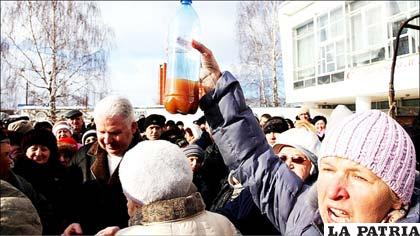 En Rusia, la calidad del agua potable es cuestionada en una protesta en las calles. Esta mujer muestra el agua que sacó del grifo, en un mitin en la ciudad de Vereya. El hombre de pelo gris en la multitud es el alcalde de la ciudad.
