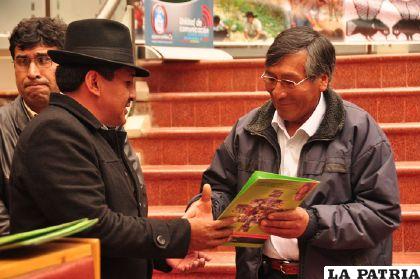 El secretario de Medio Ambiente, Felix Callata (i) entrega el certificado de egreso a Félix Chávez