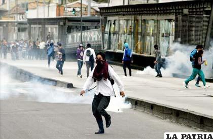Manifestantes huyen de gases lacrimógenos durante una jornada espontánea de protesta de miles de usuarios por el servicio de transporte masivo Transmilenio en Bogotá (Colombia)