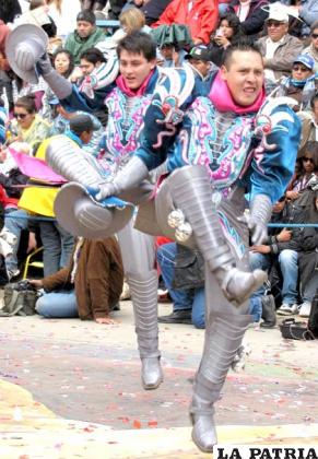 MACHO CAPORAL: Este personaje es una proyección del actual caporal, en la danza forman grupos más pequeños a manera de figuras, los pasos y coreografía son más ágiles que los de la tropa. El macho caporal representa la fuerza y juventud de los varones, este grupo de danzarines fue creado en la década del 90 del siglo pasado.
La blusa al igual a la de los otros personajes de los caporales, está hecha de lamé, con apliqués o bordados que se colocan tanto en el pecho como en la espalda, los puños están confeccionados con la misma tela del pantalón.
Lleva un sombrero en la mano derecha, forrado con la tela del traje que lleva. El pantalón es ancho a la altura del muslo, sin adornos. La faja es ancha y hecha de cartón, muchas veces se coloca la inscripción del conjunto folklórico, bordado con lentejuelas. Las botas son de cuero y van hasta las rodillas, la punta es cuadrada, no lleva adornos, pero en los costados tiene filas de cascabeles.